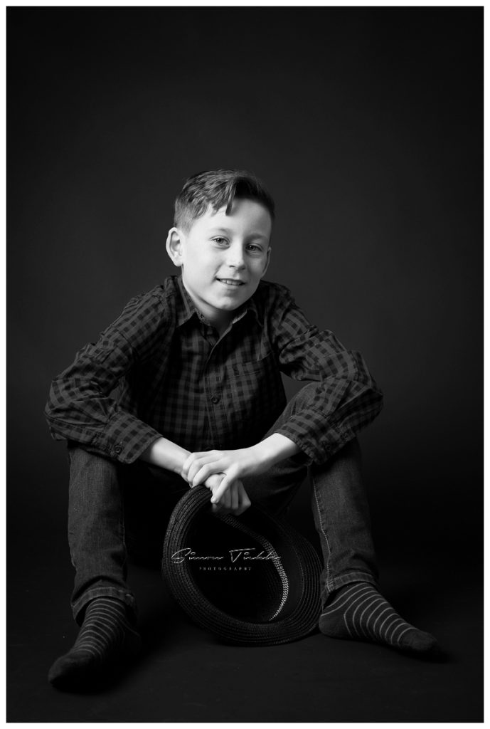 boy sat on floor holding hat